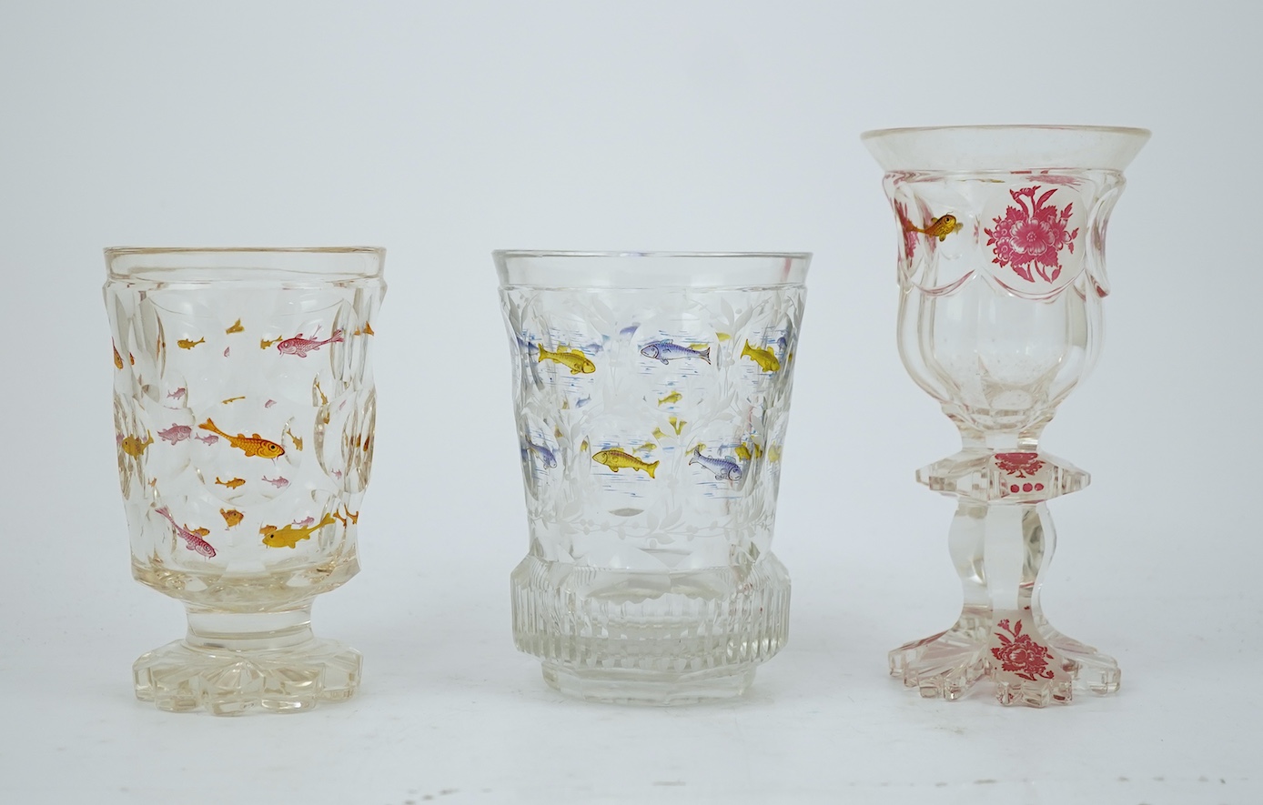 Two Bohemian transparent enamelled ‘fish’ beakers, and a similar faceted goblet, c.1840-60